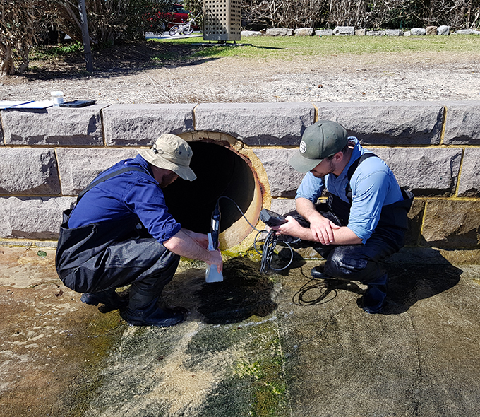 Scientists sample water at storm water drain opening at Rose Bay Beach