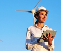 A female worker uses her ipad in front of a windfarm