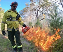 Man in protective gear engaging in controlled burn