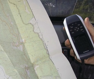 Person using a map and GPS device to navigate in a park