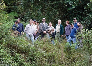 A group of Blue Mountains volunteers standing in front of green bush for a group photo.