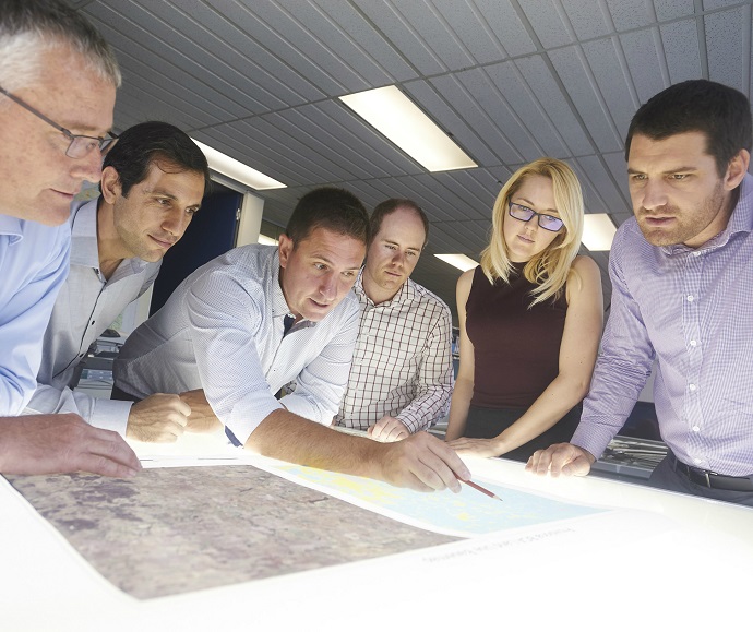 Six people looking at a document on a light table