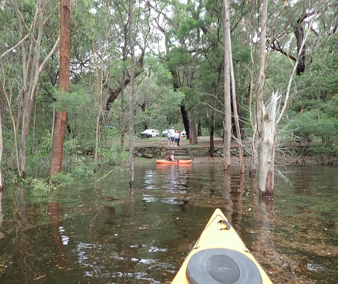 In the foreground, front of kayak on Lake Werri Berri looking across water and through trees to kayak in the background close to the stone steps, 5 March 2022