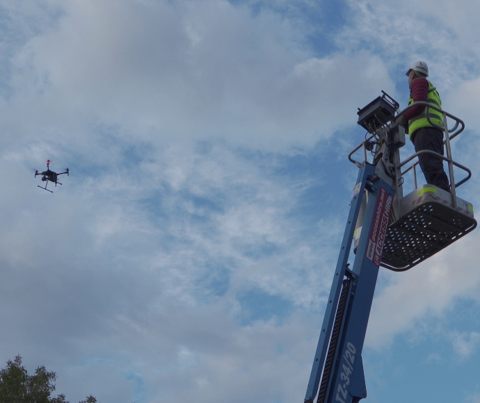 A pilot operating a drone from a cherry picker
