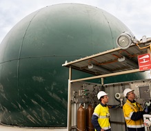 Two men looking at equipment in front of dark green dome.