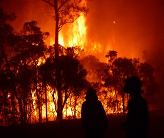Intense night time high flames fire with NPWS personnel silhouetted Windsor Downs 
