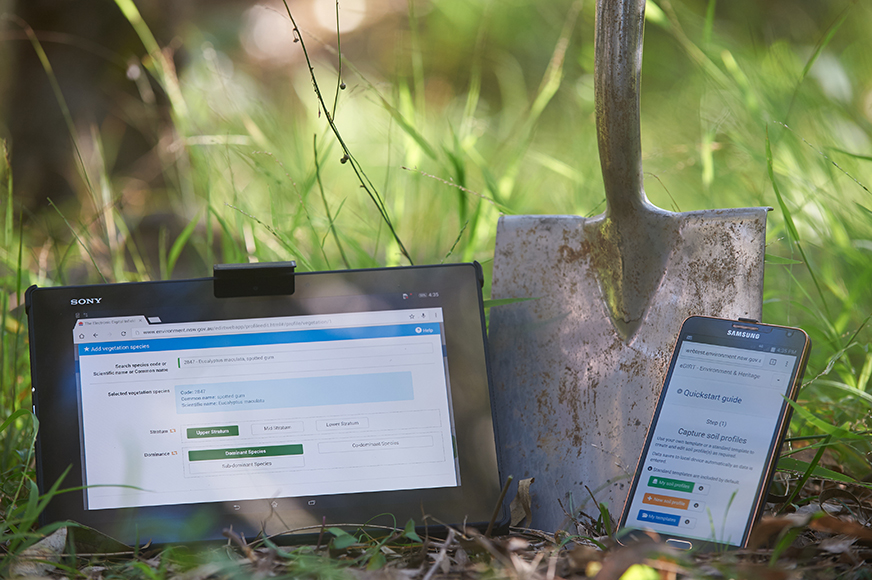 eDIRT application open on tablet and mobile devices leaning against a spade
