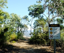 Safety sign warning visitors to take care near cliff edges at an unfenced lookout in Blue Mountains National Park
