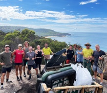 Group of smiling volunteers posing on cliff top with collected rubbish