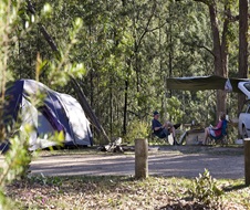 Couple sitting in campsite, with tent set up in left frame