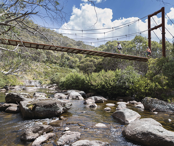 Mountain bikers travelling over a footbridge on the Thredbo Valley Track, Kosciuszko National Park.