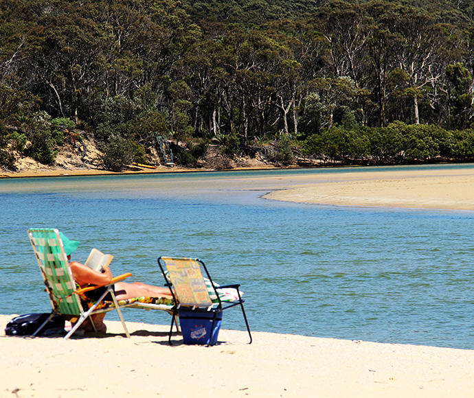 Person relaxing, deck chairs, sand bank, Nelson Lagoon Mimosa Rocks National Park