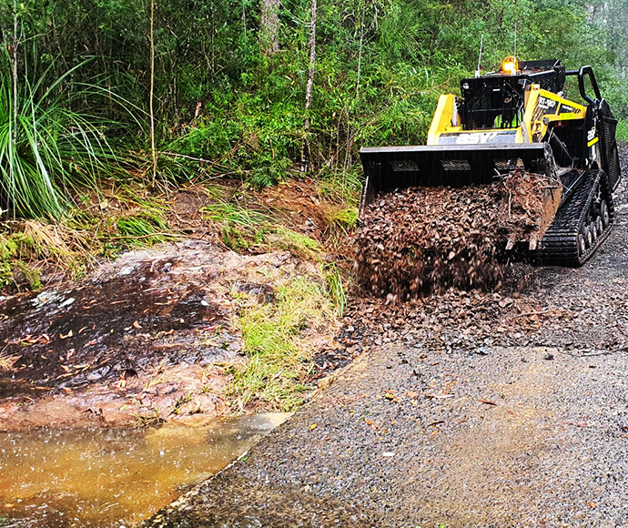 Tony Kilmurray operates a posi track compact loader to clear a causeway near Minyon Falls in Nightcap National Park