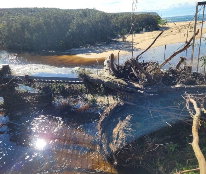 Washed away path and fencing at Royal National Park. The sun is reflecting off the flooded pathway.