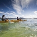 Two people are wearing sunhats and paddling their kayaks off Bradleys Head near the city of Sydney.