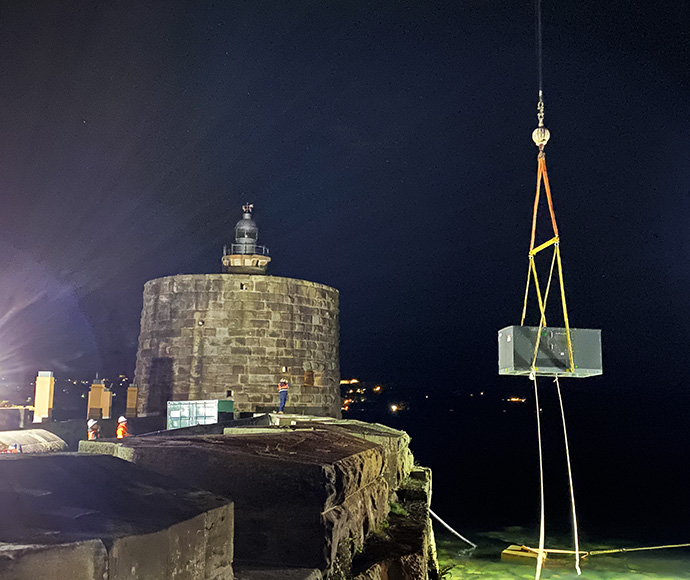 A new high voltage substation kiosk is craned into position on Fort Denison at night