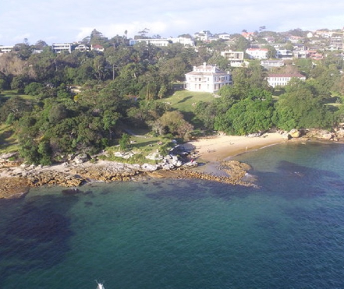 Aerial view of a 19th century home, Strickland House, surrounded by gardens and located on the foreshore in Sydney Harbour National Park