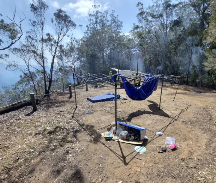 Abandoned campsite with smouldering bush behind