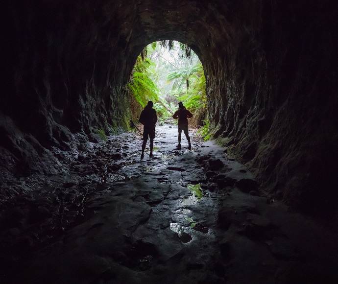 Two people standing in the light coming in from the entrance of the Glow Worm Tunnel, Wollemi National Park