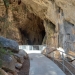 Clean cement path with guard rail leading to a huge cave-like stone arch.