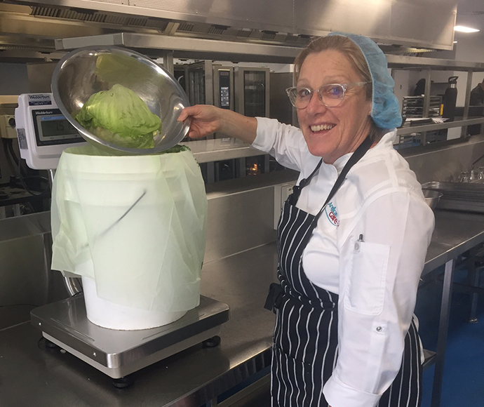 Lady at Anglican Care putting lettuce into a bucket