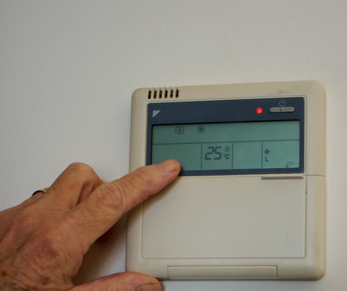 Person adjusting thermostat, energy efficiency