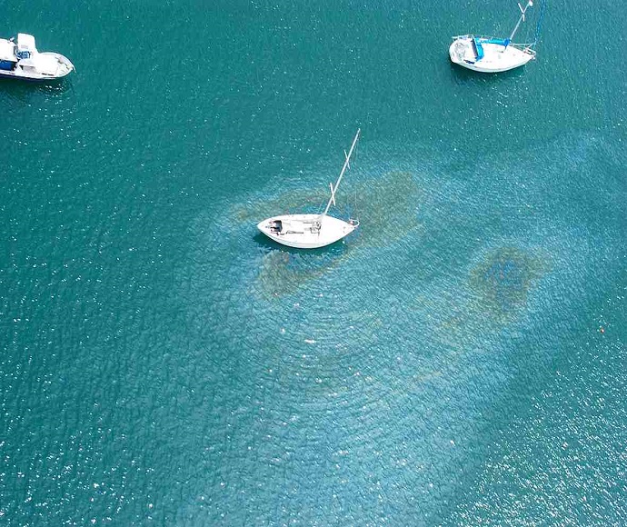 Yachts in a bay with oil leaking from one yacht