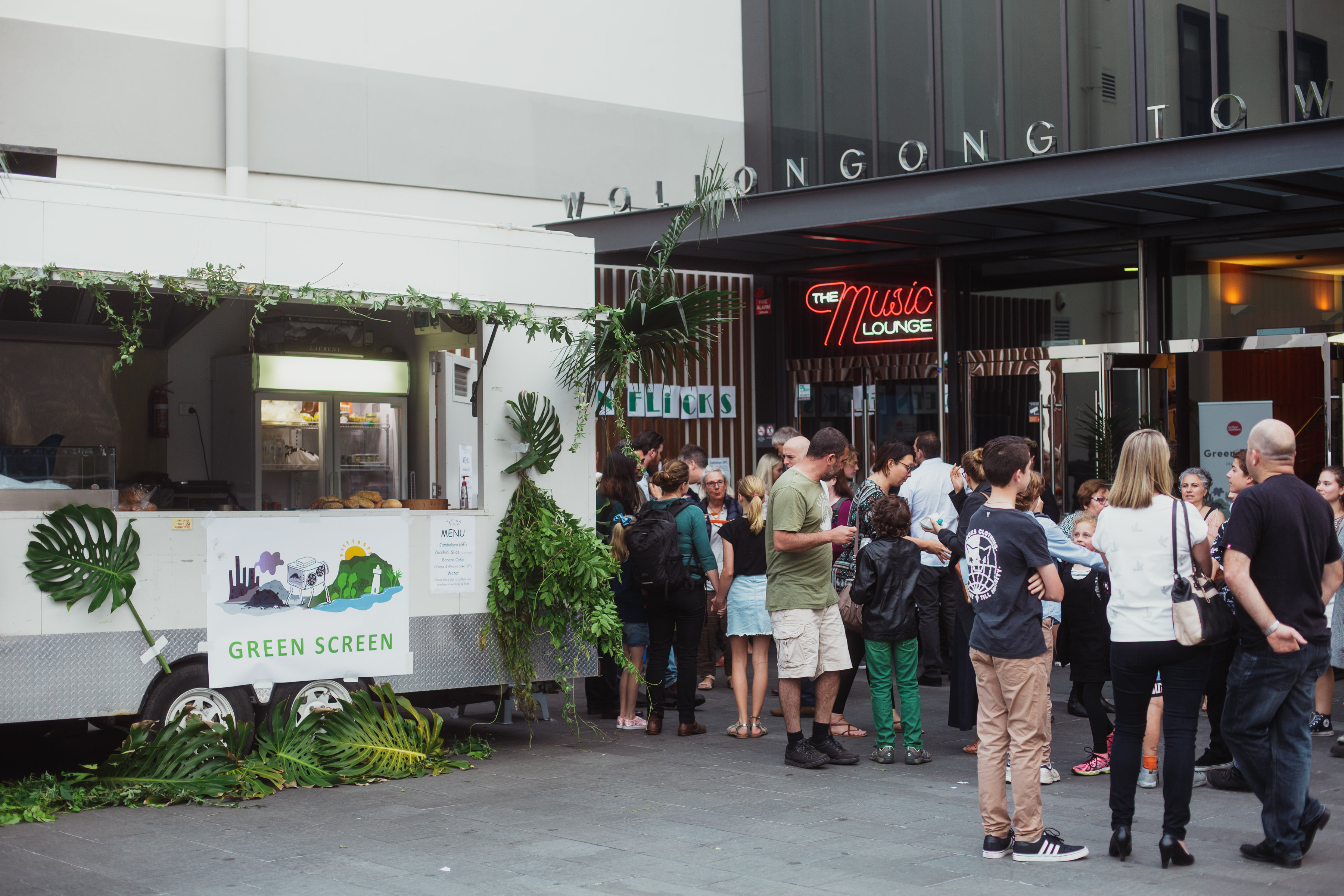 Food truck with GREEN SCREEN sign and crowd outside a venue with a Green Flicks sign