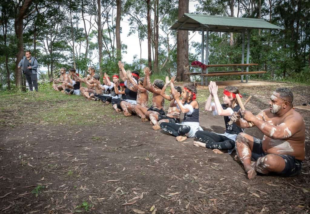An Aboriginal group are seated for a cultural performance