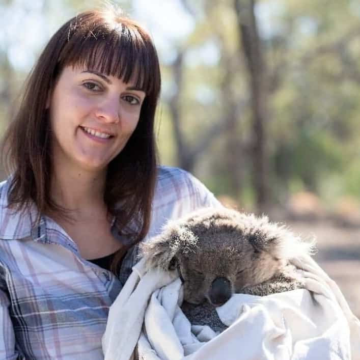 A woman holds a koala in a blanket