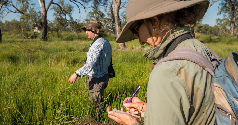 Men wearing hats walking through long grass