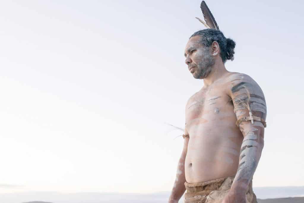 An Aboriginal man in paint with a backdrop of sky