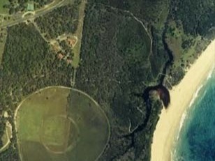 Aerial view of pipe clay creek winding through bush to meet the beach