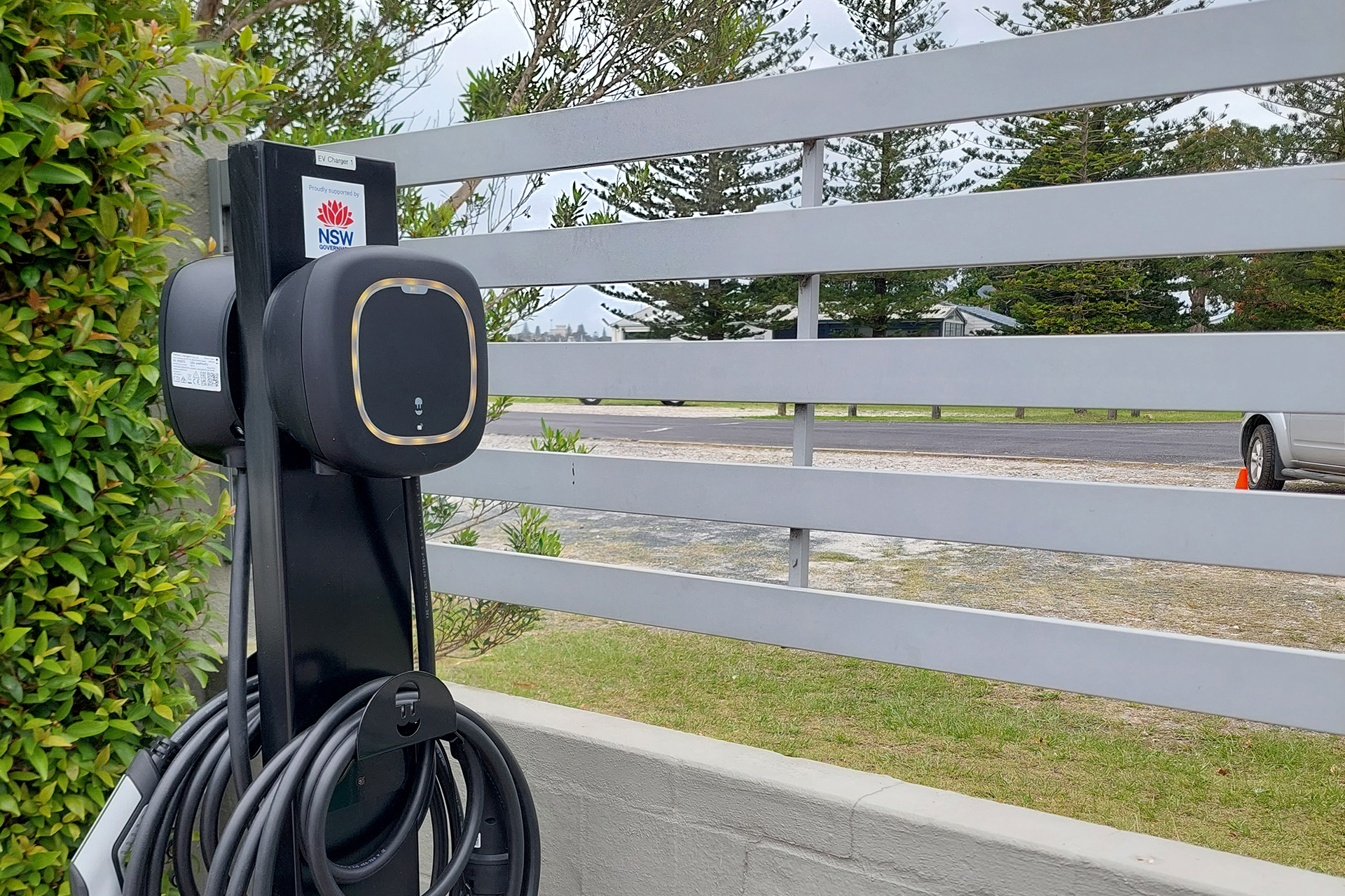 Charger on pole by white wooden fence