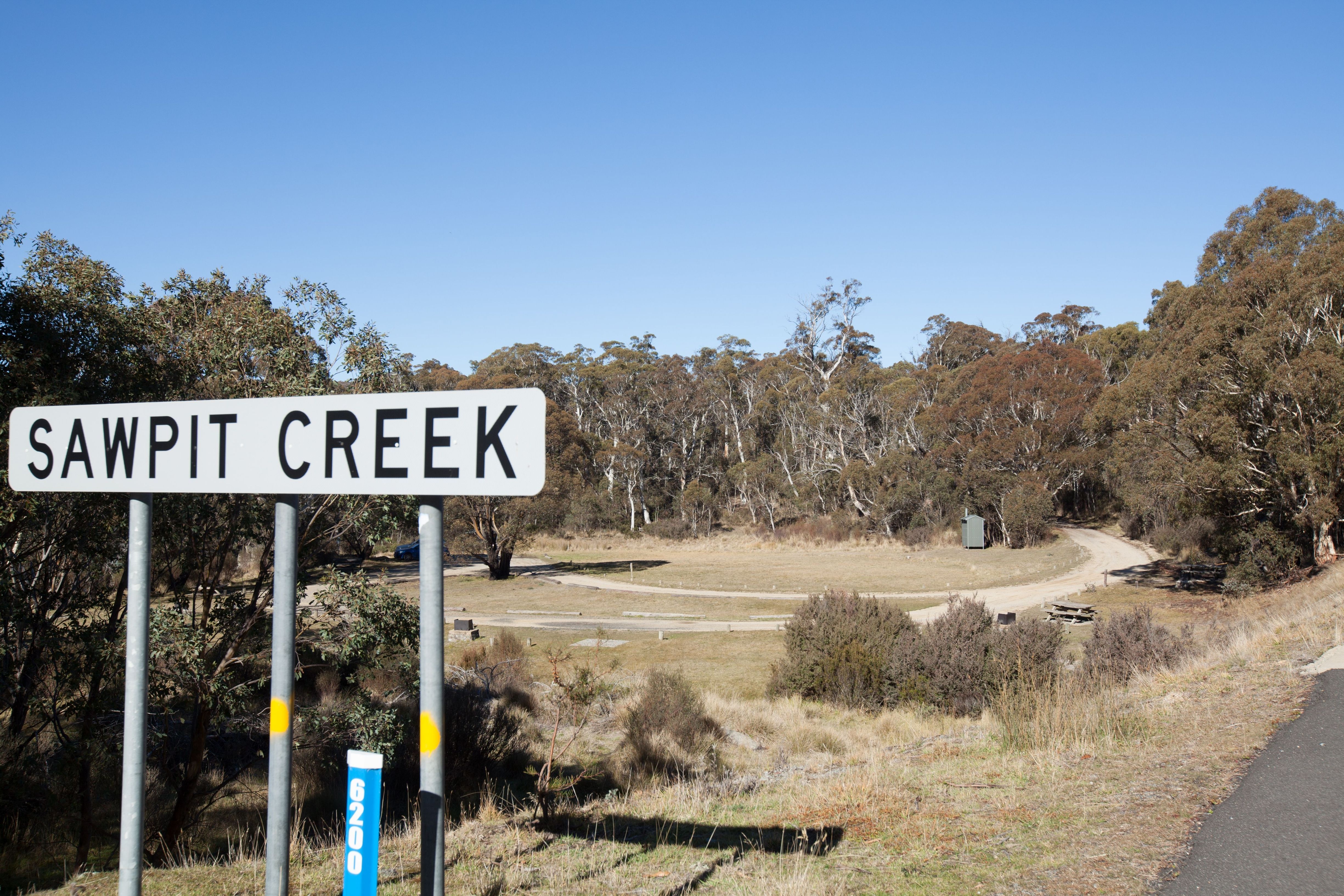 Sign of Sawpit Creek at the entrance of the Sawpit Creek picnic area, against a backdrop of lush greenery and trees.