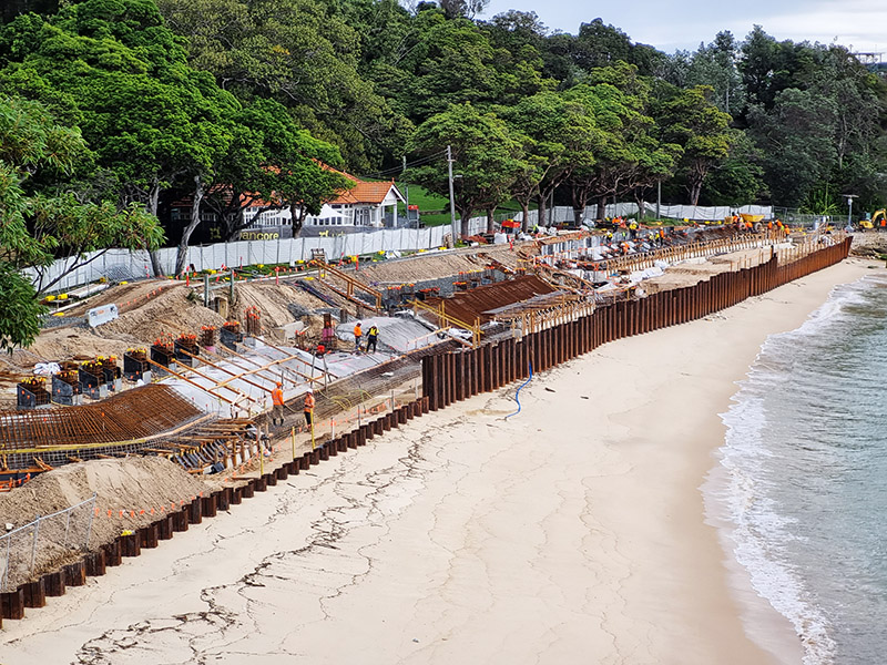 An ongoing development project at a sandy beach with workers, structural supports, and equipment