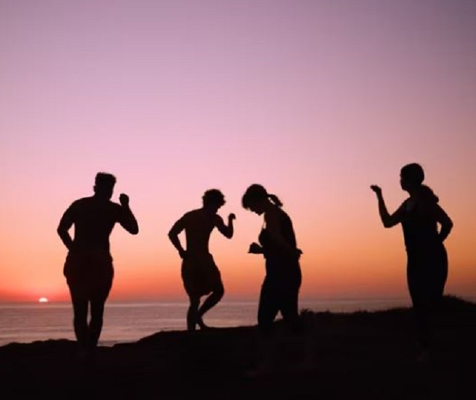 Silhouettes of four First Nations people against a sky at sunset.