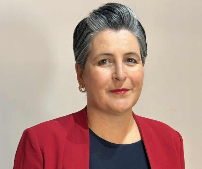 Simone wears a red blazer and black blouse against a beige background