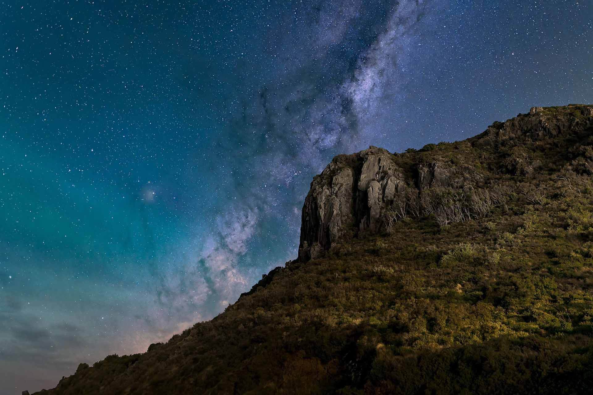 A field of stars in the night sky, above a ridge.