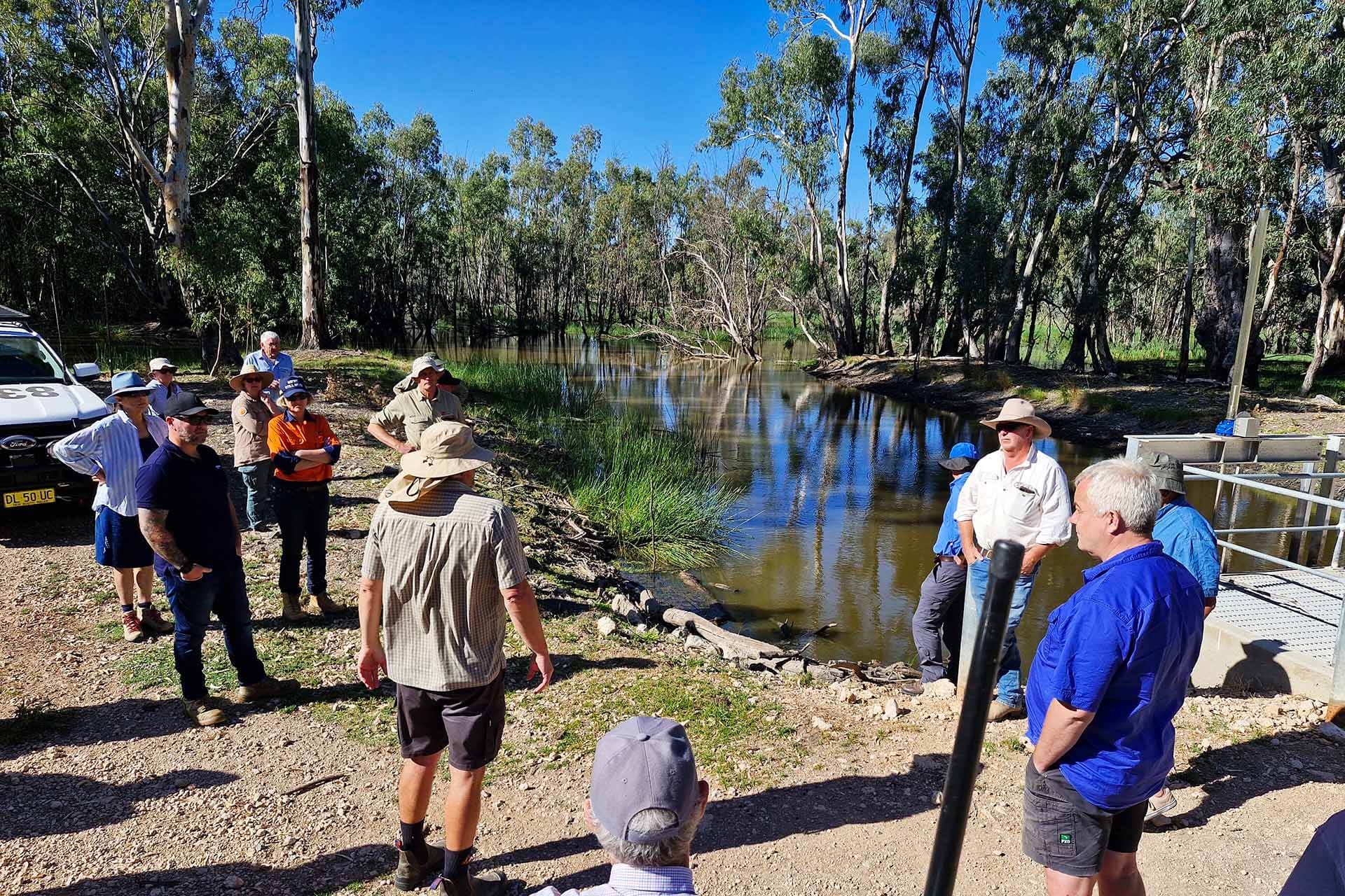 A group of people standing around a waterway.