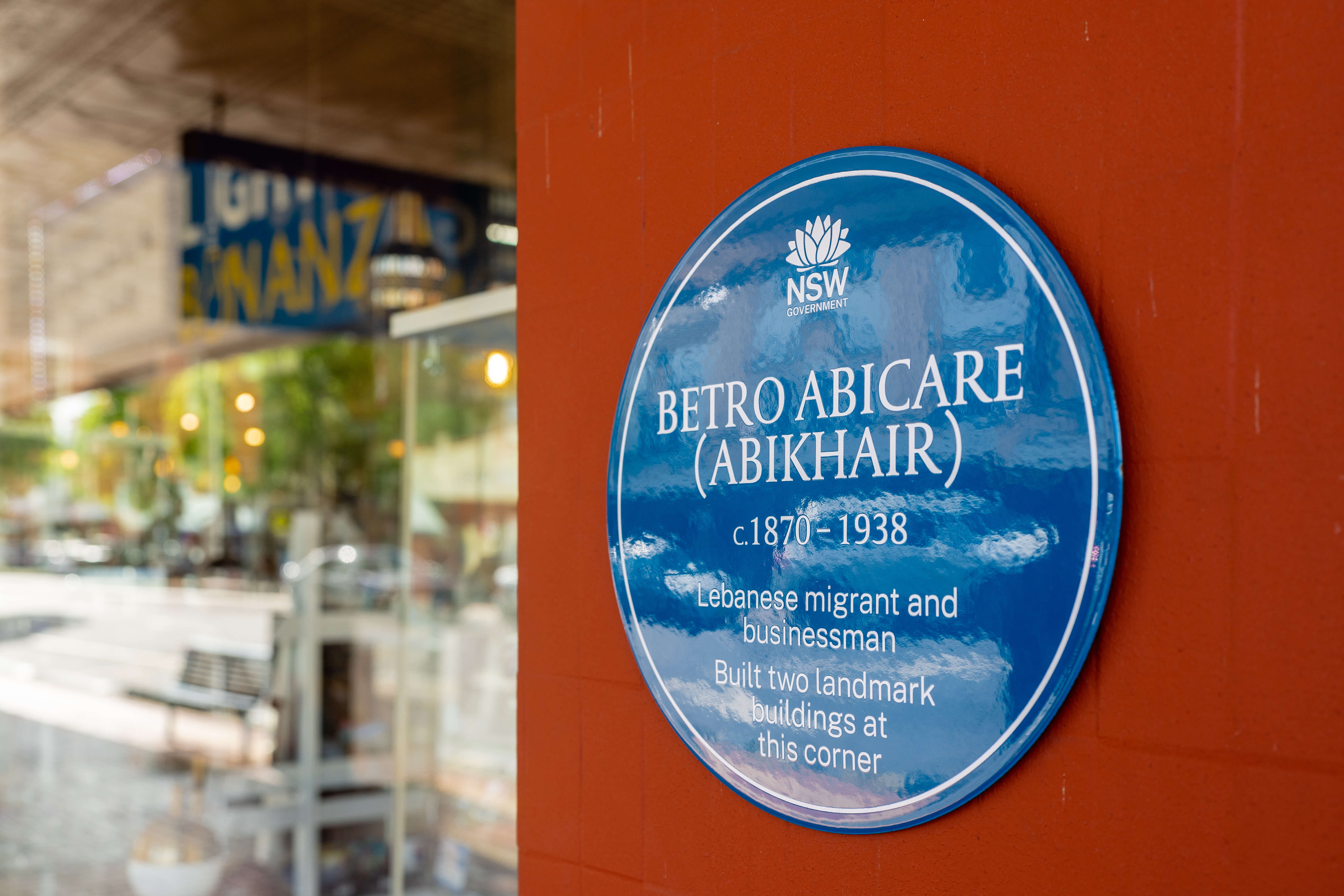 Blue Plaque honoring Betro Abicare (Abikhair), mounted on a brown wall at the former site of The Big Store in Albury, New South Wales. The plaque reads: 'Lebanese migrant and businessman. Built two landmark buildings at this corner,' recognising his contributions to the local community and architecture.