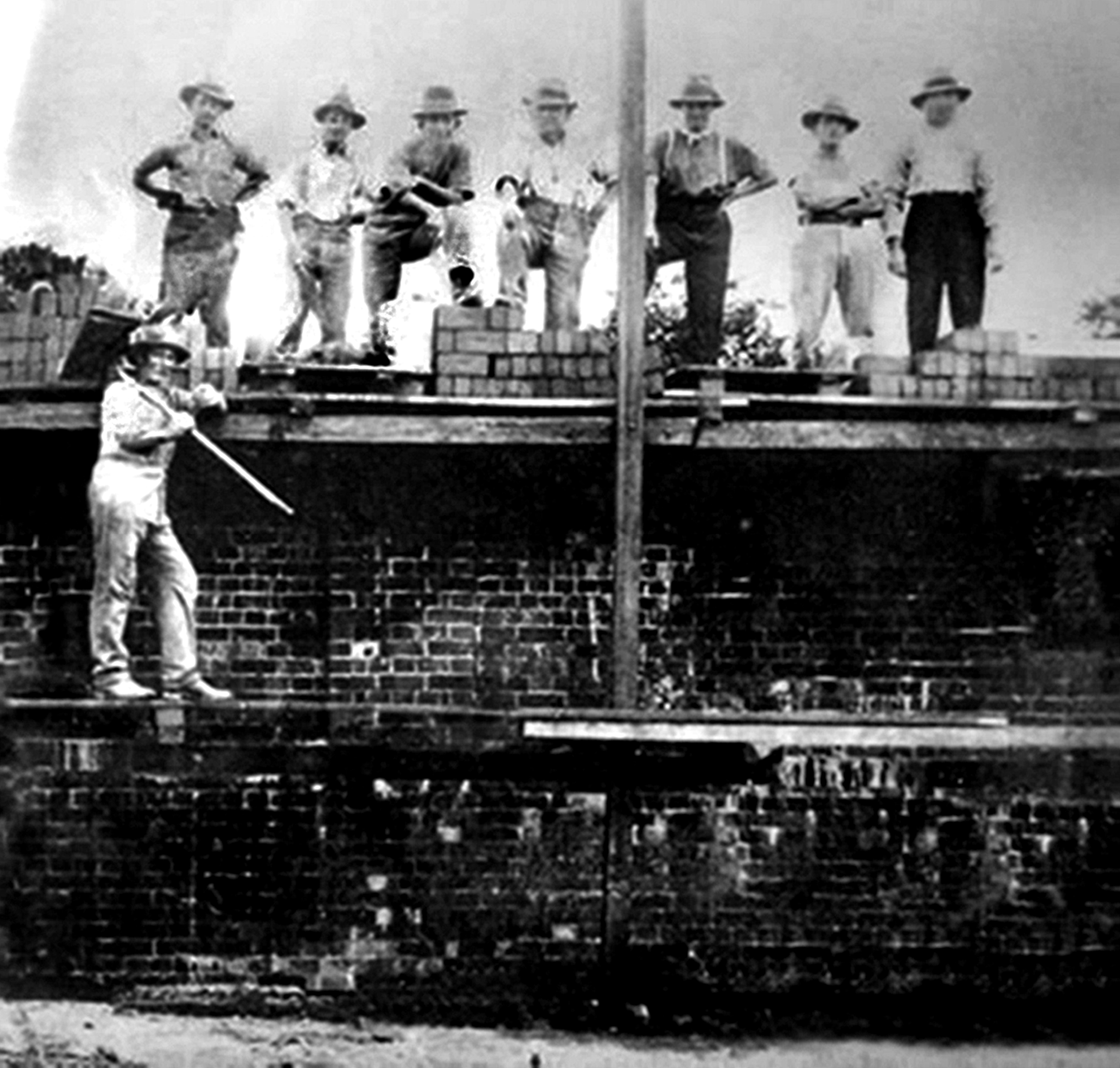 Black and white photo of 8 male workers standing on the original brickwork of the Saraton theatre in 1926.