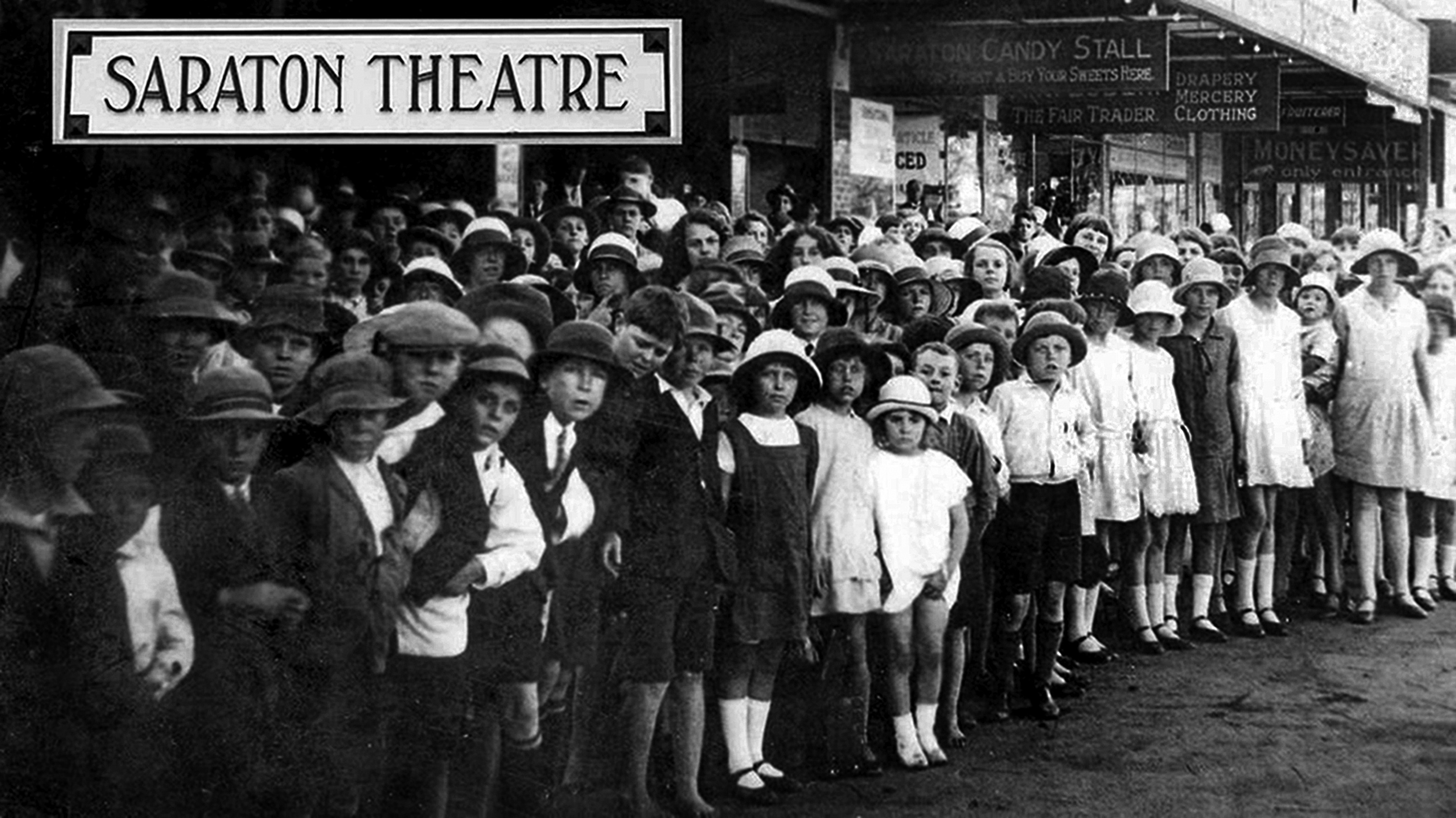 A black and white photograph of a crowd of school children lining up outside the Saraton Theatre for the opening in 1926. They were wearing hats and school uniform.