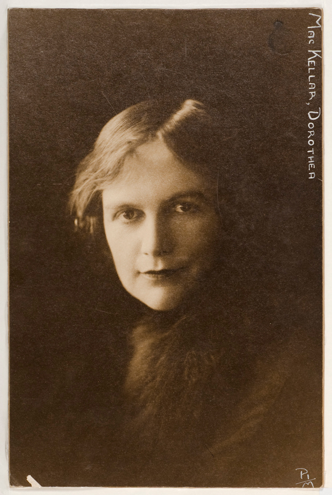 Sepia-toned portrait of Dorothea Mackellar. She has short hair and is wearing a scarf, with either a fur accessory or a dark jacket featuring a fur collar.