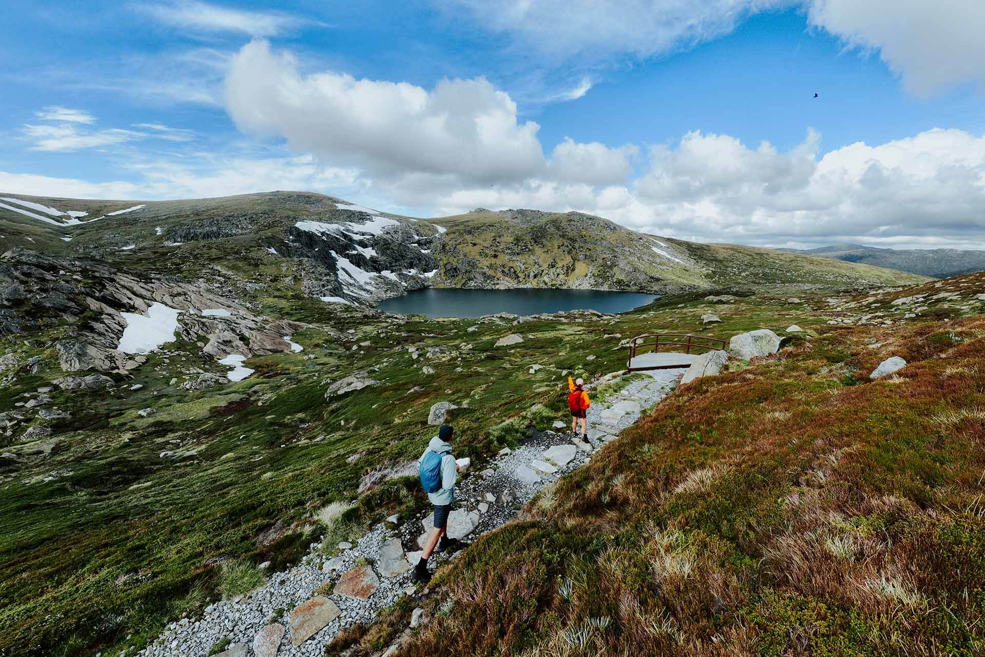 Two people walking along stone path in alpine landscape