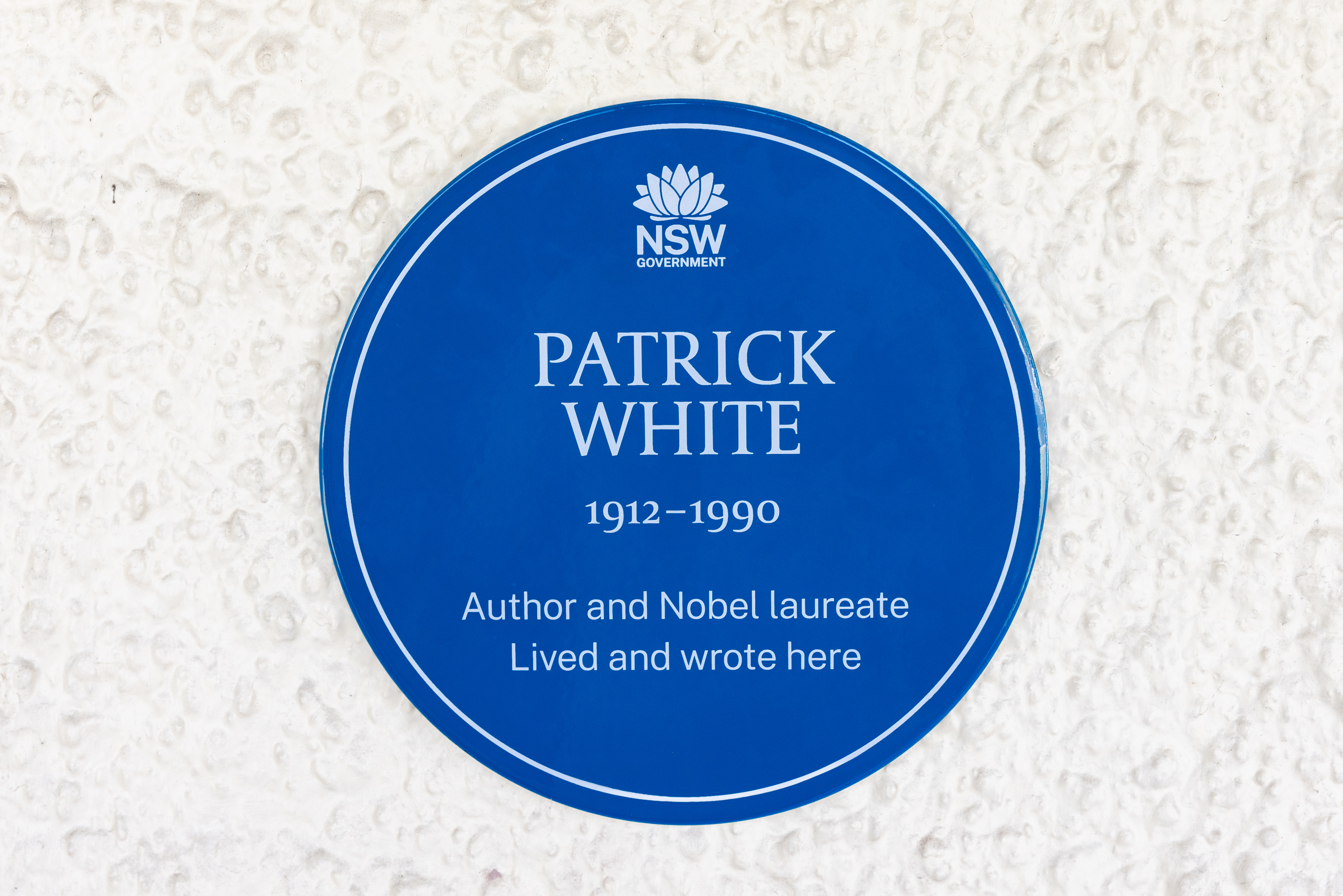 A photo of the Patrick White blue plaque. It reads 'Author and Nobel laureate. Lived and wrote here.'
