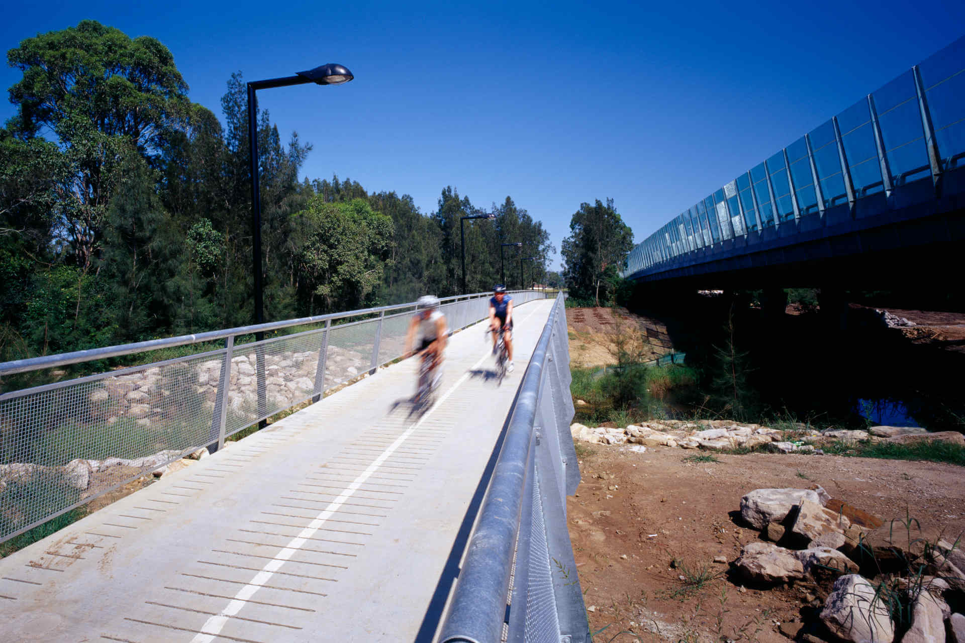The dirt, vegetation, and what is perhaps a small creek beneath a raised bike lane and a raised highway, both separate and with guard rails
