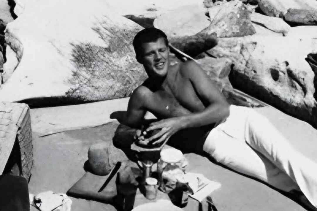 Bobby Goldsmith, a symbol for the gay community, relaxing shirtless on the beach.
