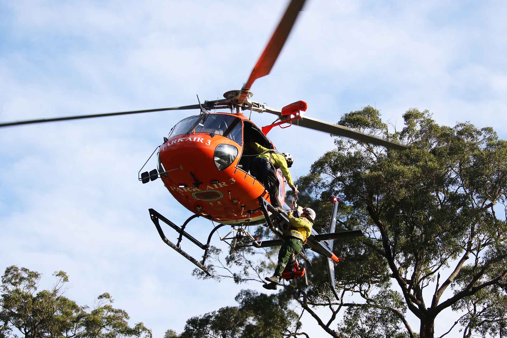 Staff being winched into hovering helicopter.