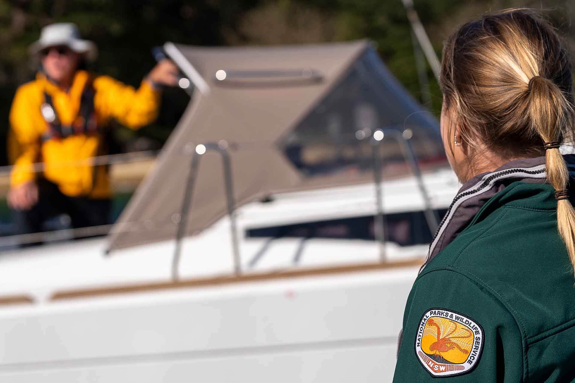NPWS officer advising person in yellow vest on nearby boat.